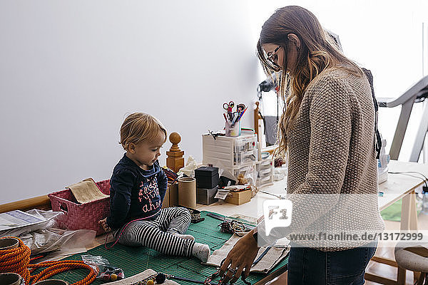Mother with little daughter at home working with fashion accessories