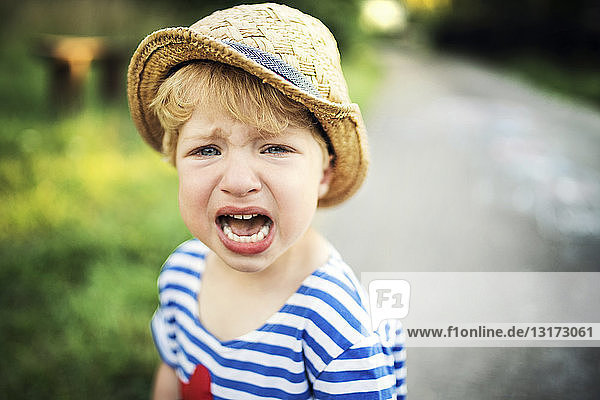 Portrait of screaming toddler wearing straw hat