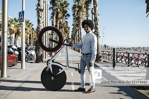 Mittelgroßer erwachsener Mann steht auf der Straße und zeigt sein Fixie-Bike