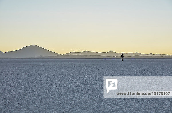 Bolivien Salar de Uyuni Frau geht bei Sonnenuntergang auf dem Salzsee spazieren