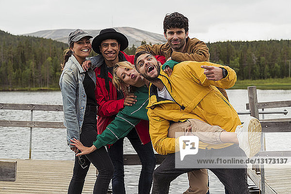 Finnland  Lappland  Porträt fröhlicher  verspielter Freunde auf einem Steg an einem See