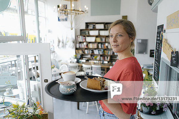 Junge Frau serviert Kaffee und Kuchen in einem Café