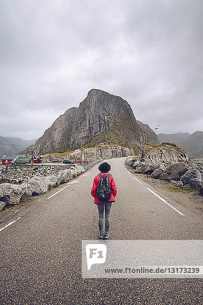 Norwegen  Lofoten  Hamnoy  Rückenansicht eines Mannes mit Rucksack  der auf einer leeren Straße steht