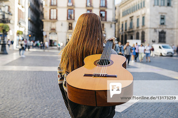 Red-haired woman playing the guitar in the city
