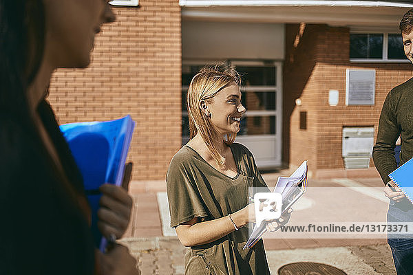 Lächelnde Studenten  die mit Dokumenten im Freien stehen
