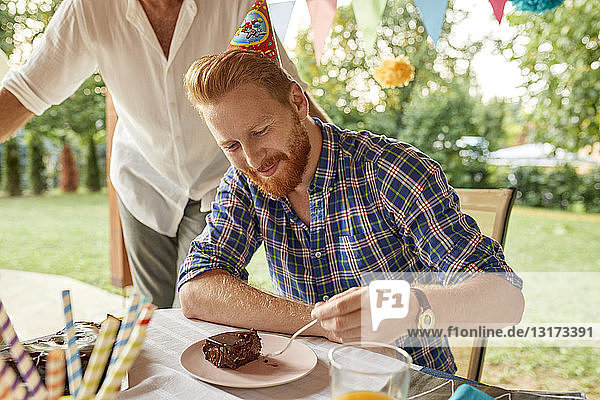 Man eating cake on a birthday garden party