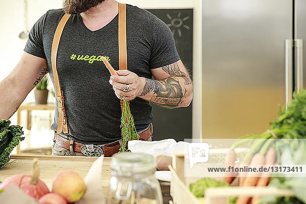 Veganer hält Karotte in seiner Küche