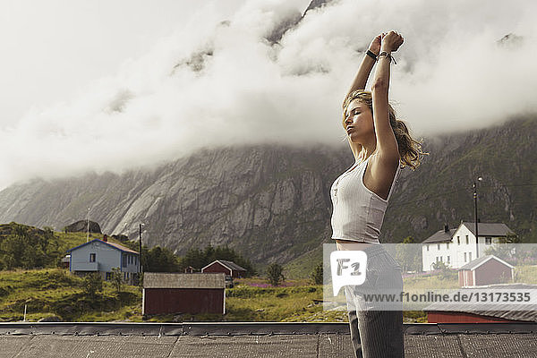 Young woman standing in nature  stretching  Lapland  Norway