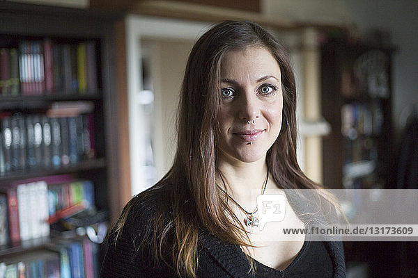 Portrait of smiling woman with piercings at home