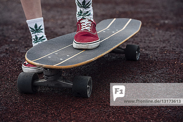 Woman's legs in socks and sneakers standing on carver skateboard