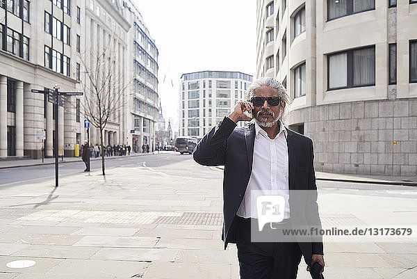 Großbritannien  London  Porträt eines älteren Geschäftsmannes mit Sonnenbrille am Telefon