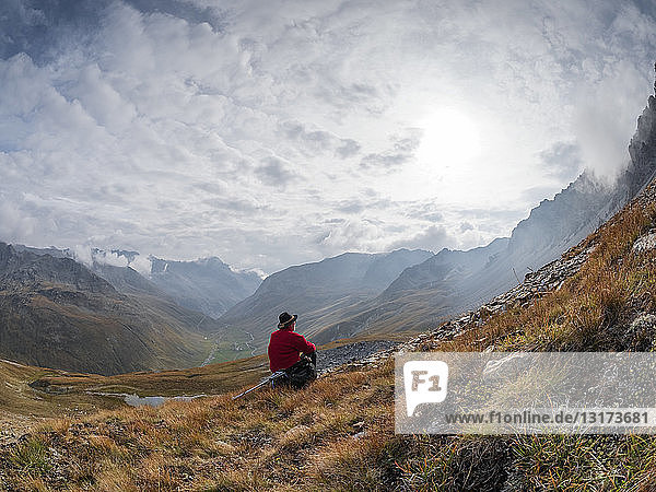Grenzregion Italien Schweiz  älterer Mann macht Pause vom Wandern in der Berglandschaft am Piz Umbrail