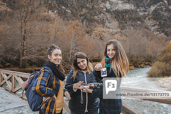 Spanien  Porträt von drei jungen Frauen mit Sofortbildern auf einer Brücke im Nationalpark Ordesa