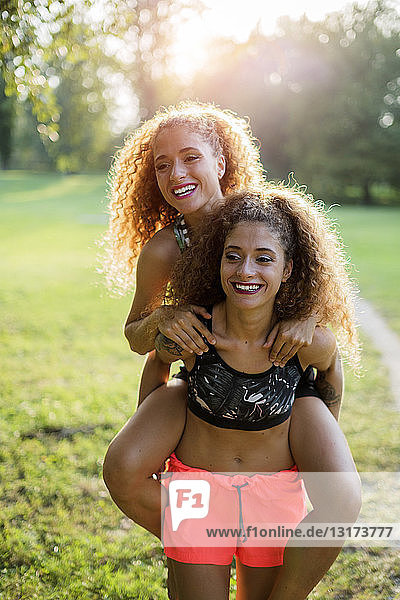 Porträt einer glücklichen jungen Frau  die ihre lachende Zwillingsschwester Huckepack nimmt