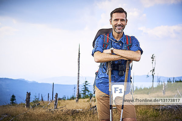Porträt eines lächelnden Mannes  der eine Pause vom Wandern in den Bergen einlegt