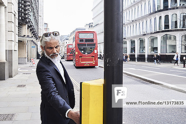 UK  London  bearded senior businessman pressing traffic lights button