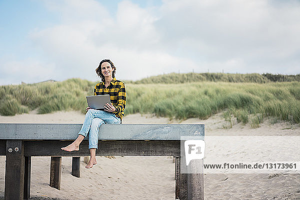 Mature woman sitting on boardwalk at the beach  using laptop