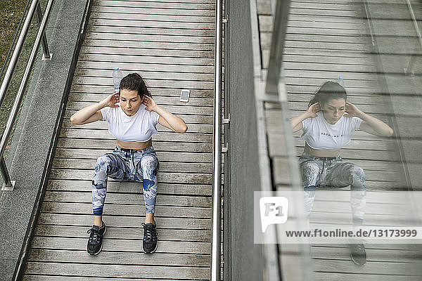 Young woman doing situps on a footbridge