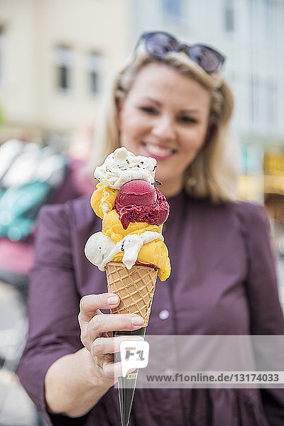 Frau hält Eiswaffel mit verschiedenen Eissorten in der Hand