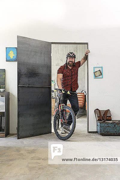 Portrait of smiling man with bicycle in office
