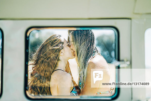 Lesbisches Paar macht eine Autoreise  küsst und umarmt sich in der Natur