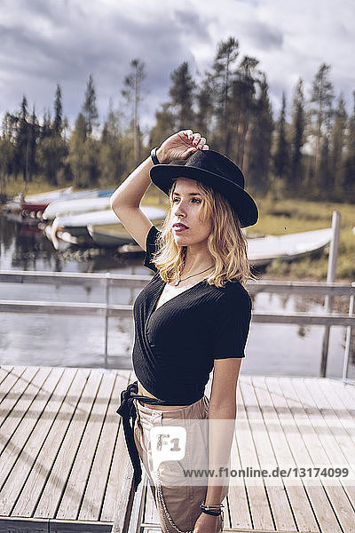 Schweden  Lappland  Porträt einer modischen blonden Frau mit schwarzem Hut auf einem Steg stehend