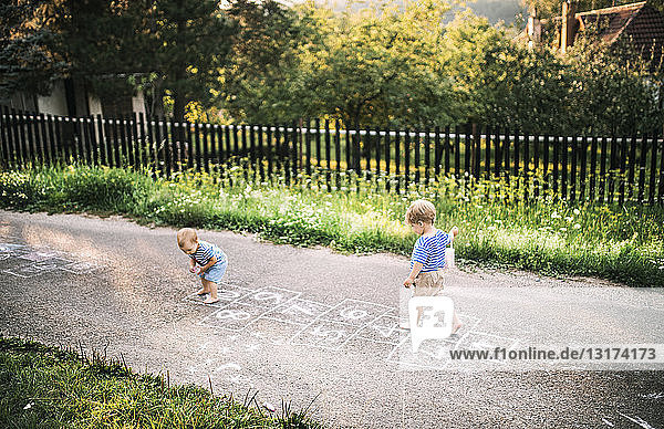 Kleinkind und kleine Schwester spielen im Freien