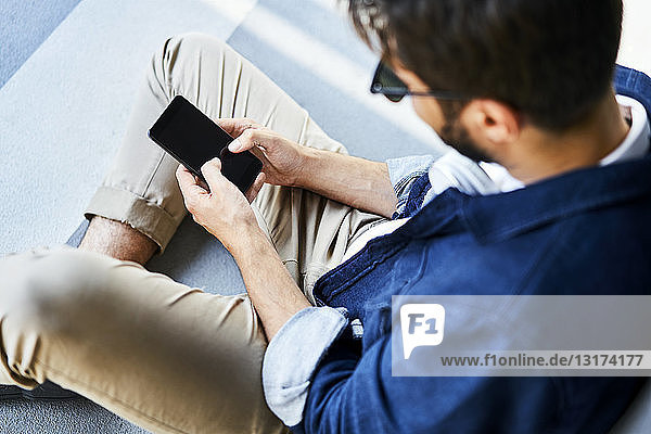 Young man sitting on the ground text messaging