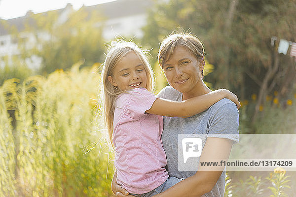 Portrait of smiling mother carrying daughter in nature