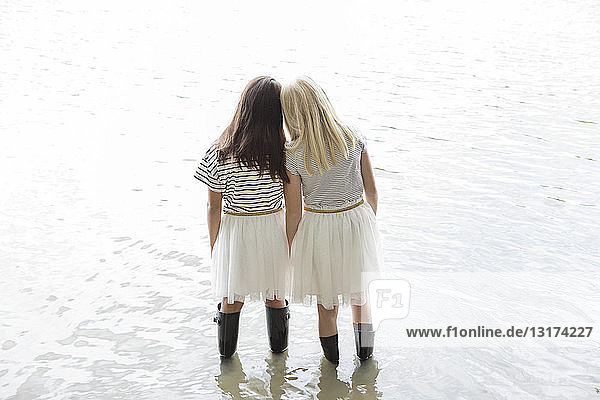 Rückenansicht von zwei besten Freunden  die Kopf an Kopf in einem See stehen