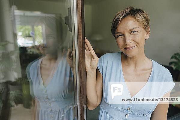 Portrait of smiling woman at French window