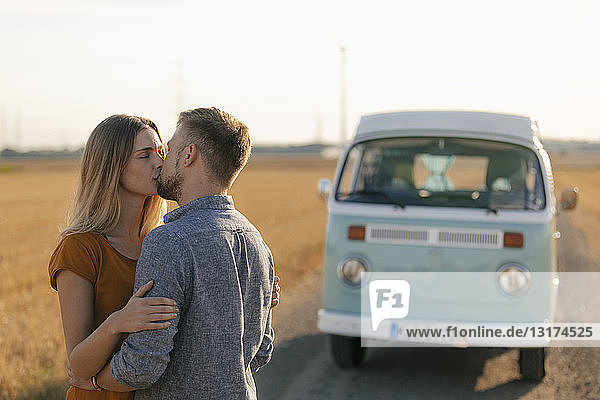 Young couple kissing at camper van in rural landscape