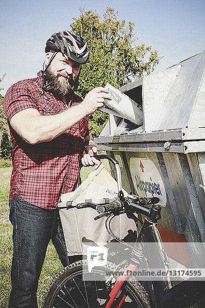Porträt eines Radfahrers beim Recycling von Altpapier in einer Papierbank