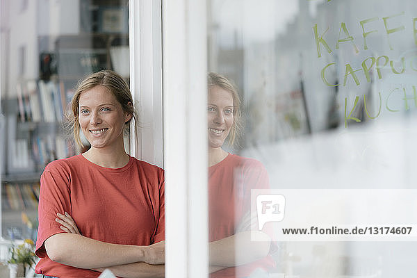 Porträt einer lächelnden jungen Frau vor französischer Tür in einem Café