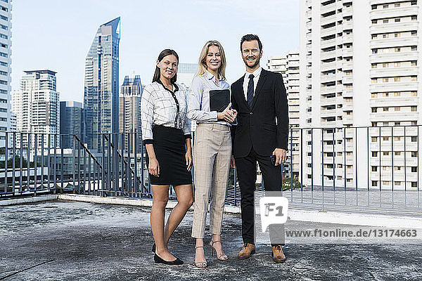 Group of successful business people on city rooftop  holding digital tablet