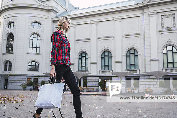 Fashionable young woman with shopping bag walking along