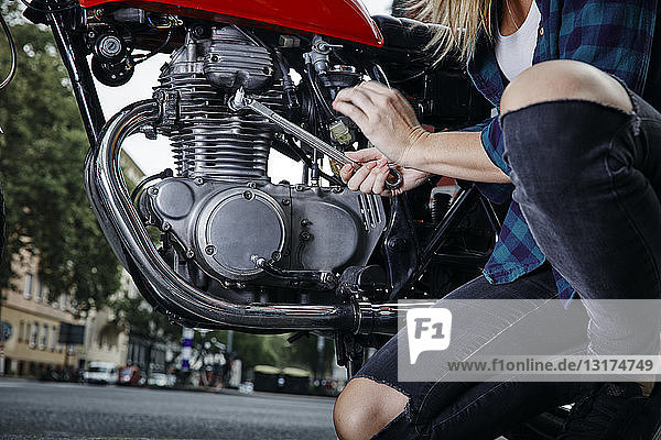 Young woman working on motorcycle