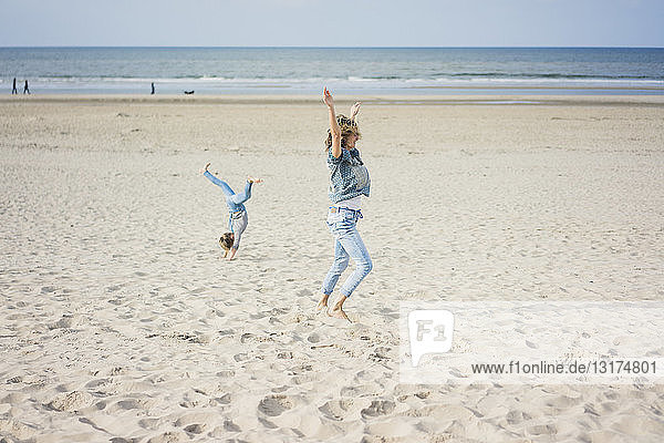 Mother and daughter having fun  cartwheeling on the beach