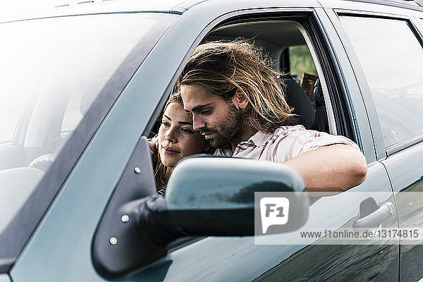 Zärtliches junges Paar in einem Auto