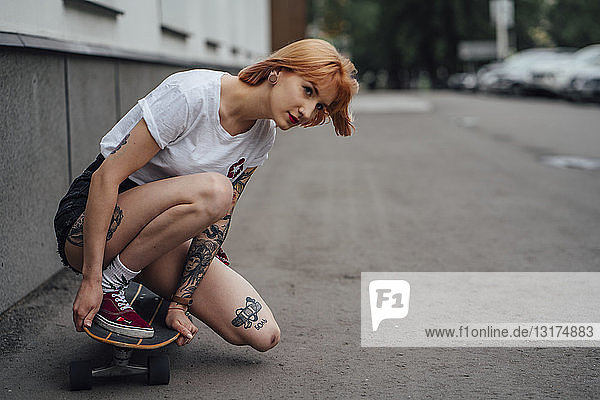 Junge Frau kauert auf einem Carver-Skateboard auf einer Straße