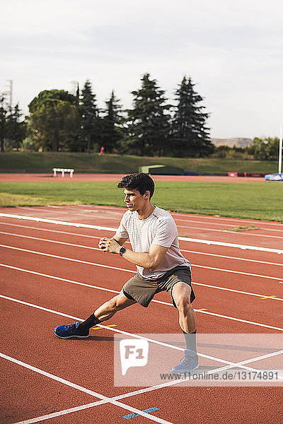 Athlete sitting doing warm-up exercises on a tartan track