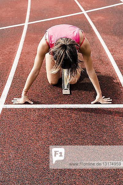 Teenage runner in starting position on race track