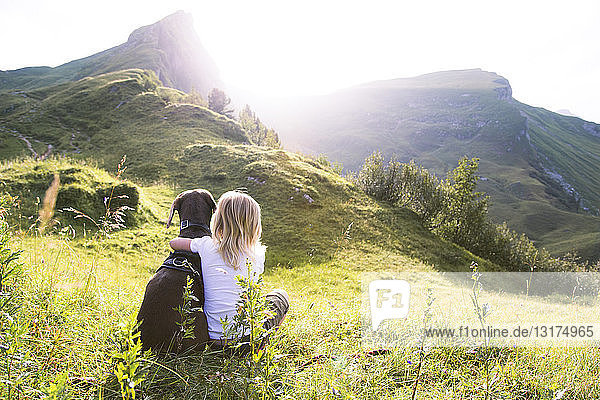 Austria  South Tyrol  young girl sitting with dog on meadow
