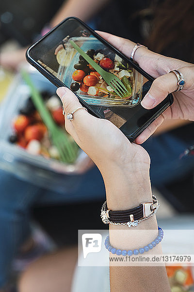 Ein Mädchen fotografiert einen Salat mit ihrem Smartphone  Nahaufnahme