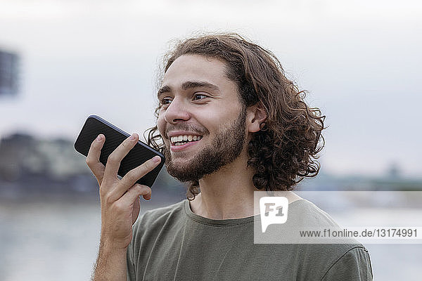 Portrait of happy young man using smartphone outdoors