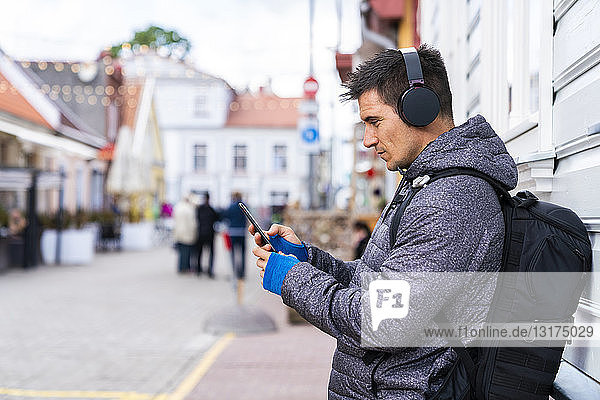 Mann mit Handy und Kopfhörern in der Stadt