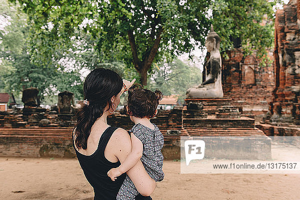 Thailand  Ayutthaya  Mutter und Tochter betrachten eine Buddha-Statue im Wat Mahathat