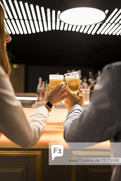 Close-up of couple clinking beer glasses in a bar