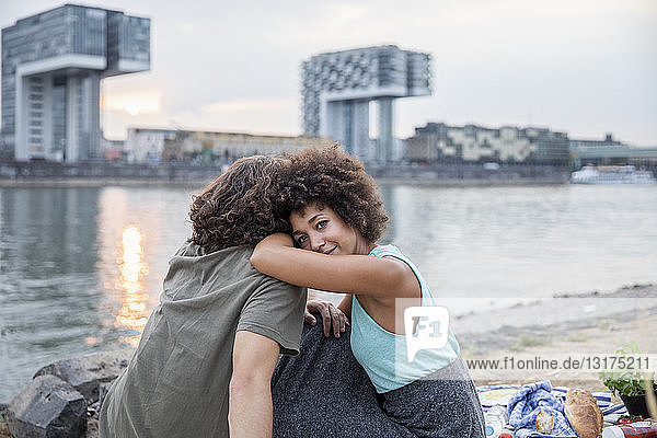 Germany  Cologne  couple relaxing at the riverside at sunset