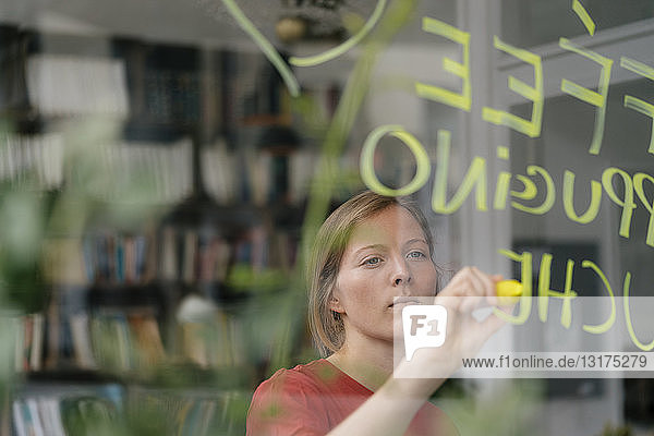 Junge Frau schreibt Angebot auf Fensterscheibe in einem Cafe